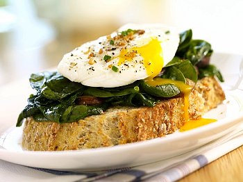 A breakfast meal of spinach, mushrooms and an egg on top of a piece of toast