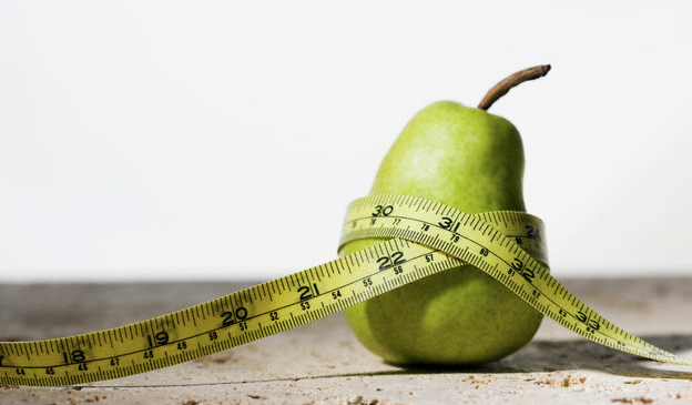 A pear wrapped with a yellow tape measure