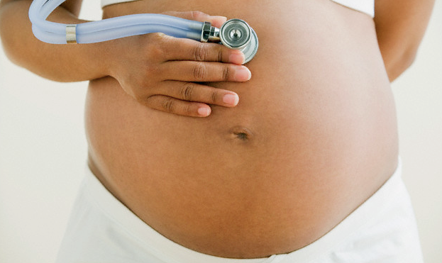 pregnant woman hold stethoscope against belly
