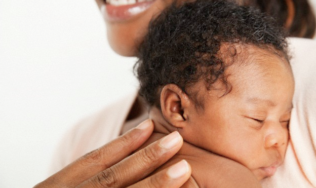 A smiling mother holding her newborn baby