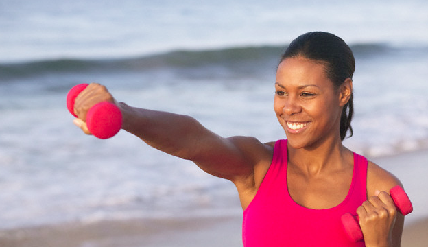 african american woman on the beach with a weight in hand