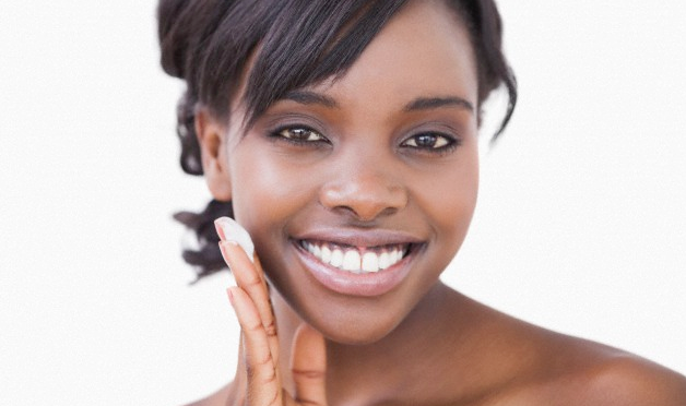 A smiling touching touching her face with her fingertips, applying cream.