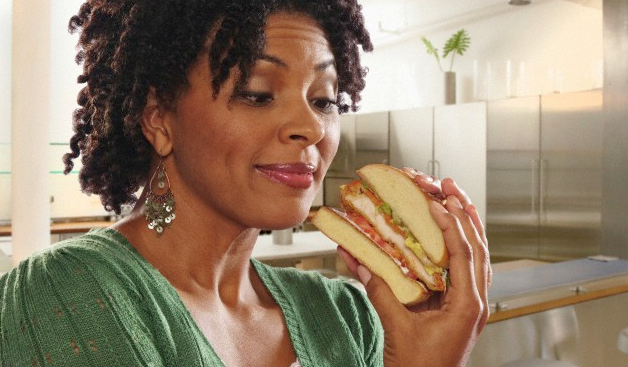 A woman holding and looking at a sandwich