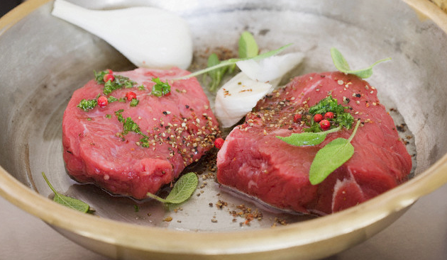 Two steaks cooking in a skillet