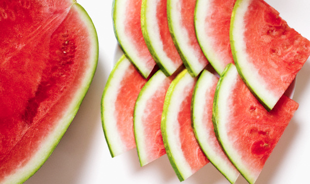 Watermelon slices sitting next to half of a watermelon