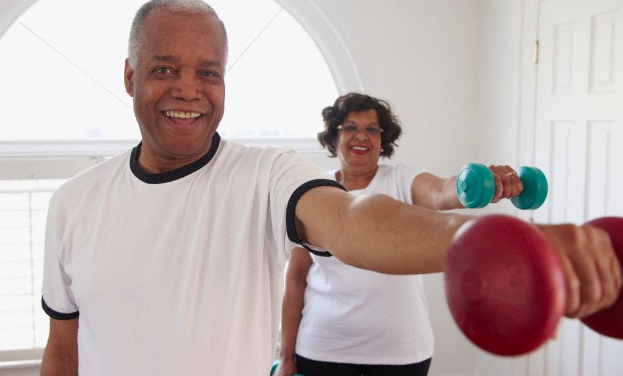 An older couple lifting weights in their home