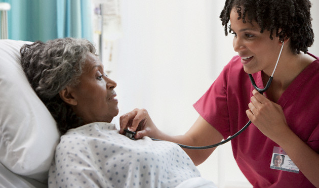 A doctor checking an elderly patient's heart with a stethoscope
