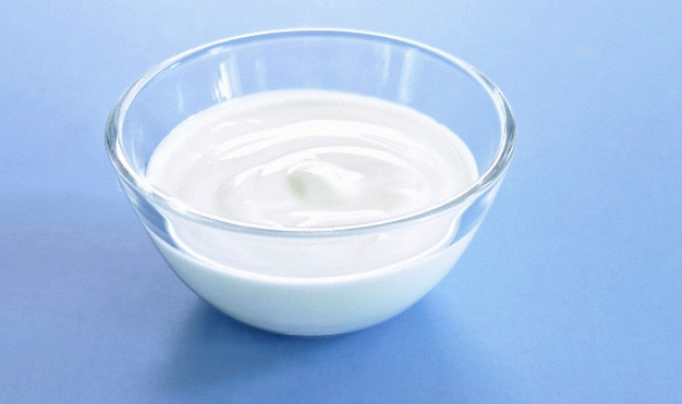A bowl of greek yogurt sitting on a blue surface
