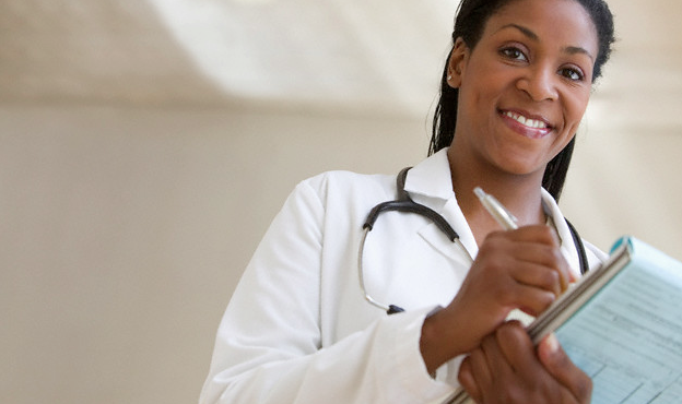 A smiling doctor writing notes in a chart