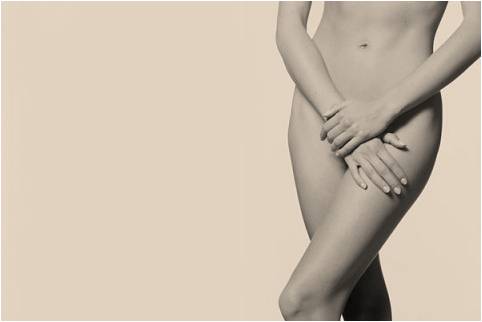 black and white image of woman with no clothes on, arms crossed covering lower region