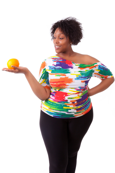 Overweight young black woman holding an orange