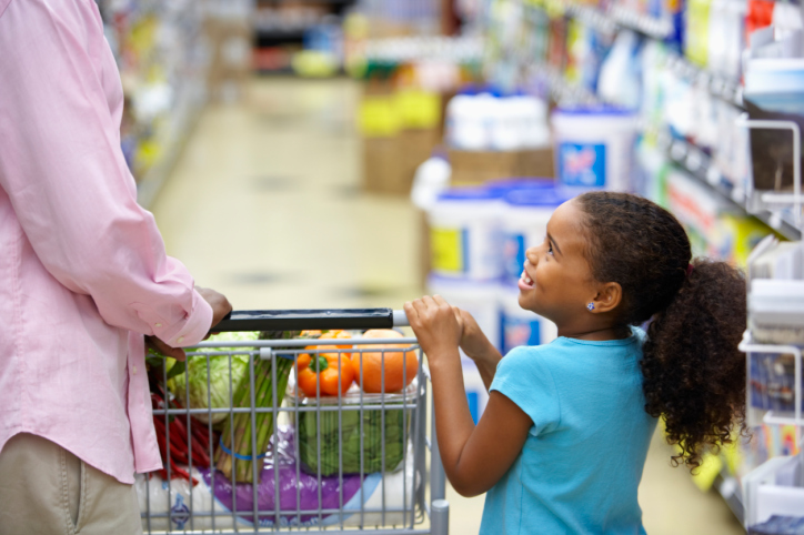 african american girl holding on to a cart in grocery store