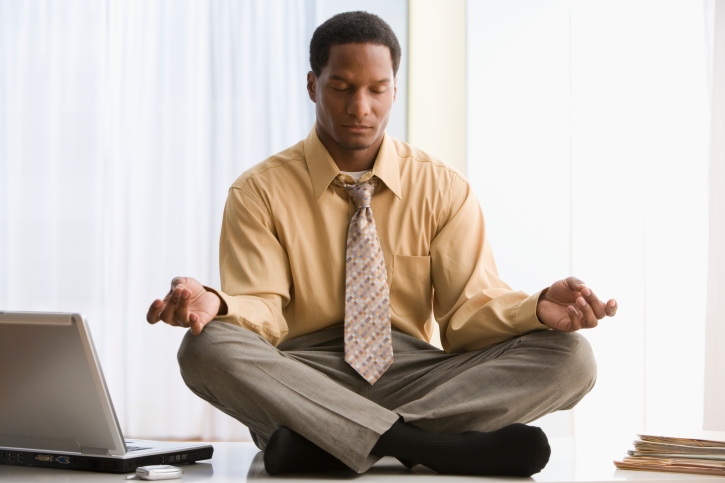 Black African American businessman meditating on desk