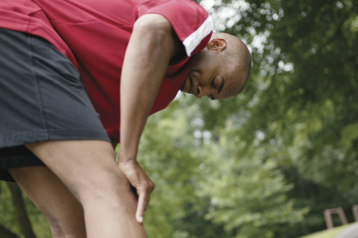 Tired African American man bending over outdoors
