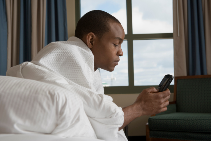 Man lying in bed and checking cell phone