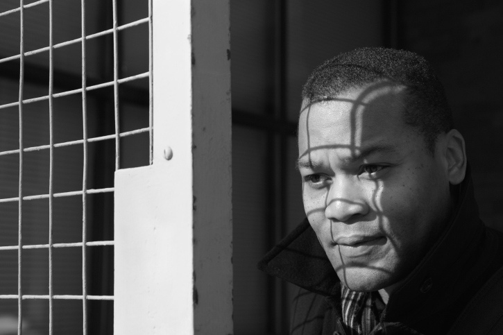 black and white photo of man looking out of window