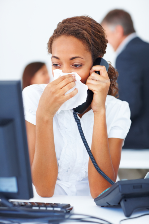 Sick young business woman blowing her nose while speaking on the
