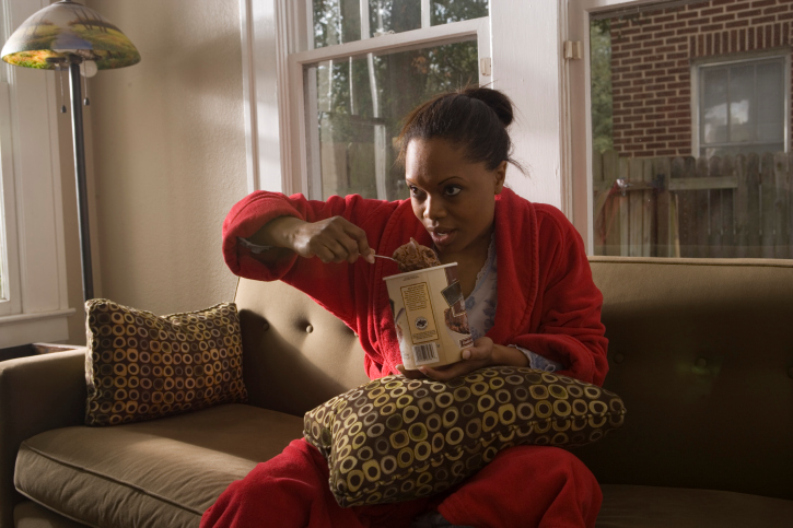 Young woman in gown eating an ice cream on a sofa