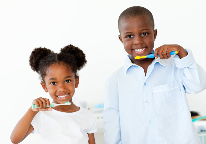 Smiling brother and sister brushing their teeth