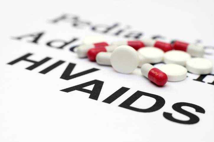 hiv aids in background with pills sitting on top of the words