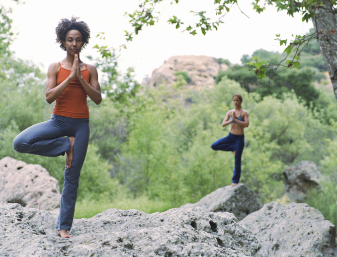 two women doing yoga poses on rocks