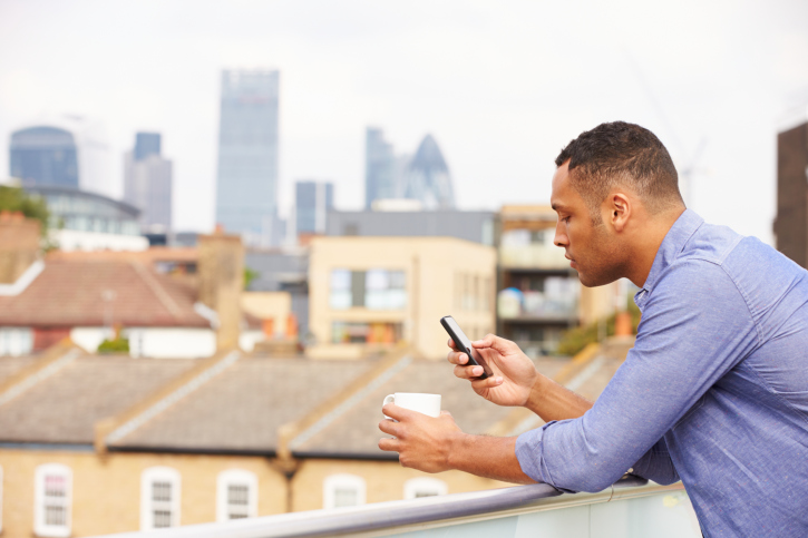 man looking at phone with coffee