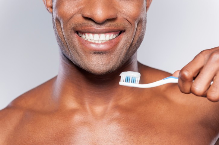 man smiling holding up toothbrush