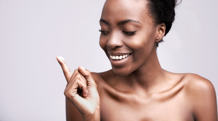 african american woman holding face cream