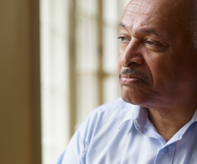 Older African American man looking out window