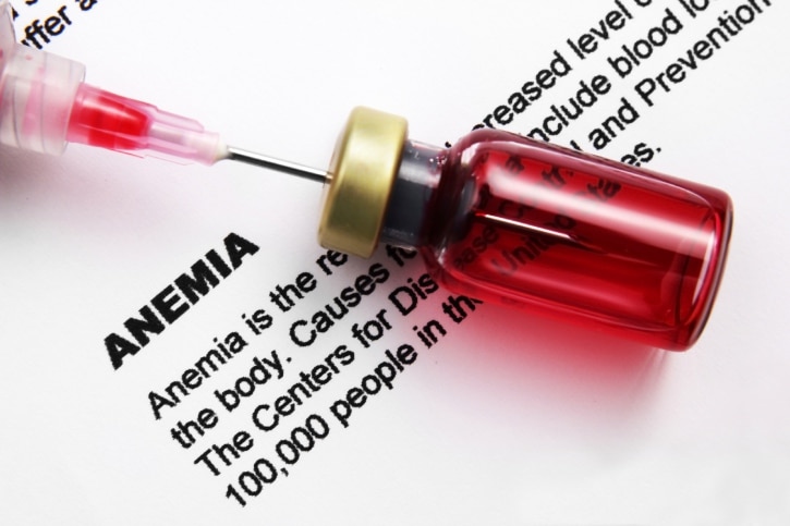 vial with needle sitting on top of a paper with the description of anemia typed on it