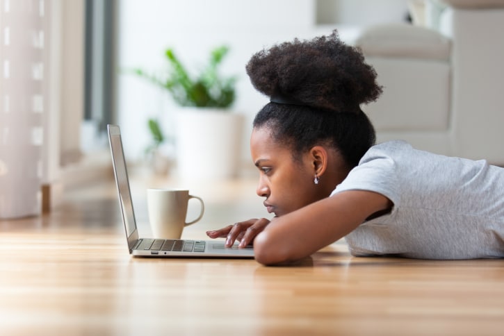 African American Black woman sad serious using a laptop in her living room