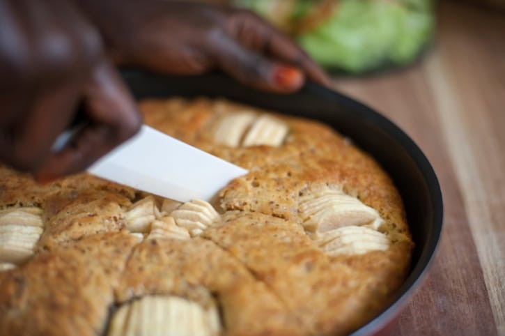African American Black Woman is cutting a piece of apple cake