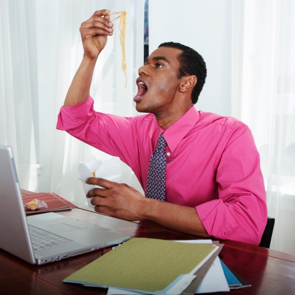 African American Black hungry man eating at desk at work