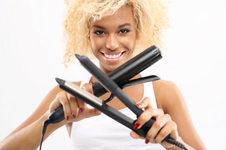 African American woman holding curling iron and flat iron