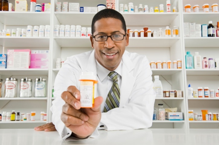 African American man pharmacist holding prescription bottle