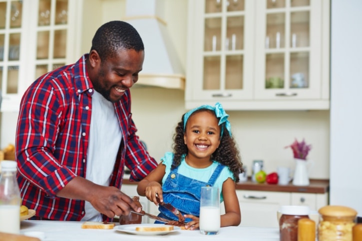 African American Black father and daughter making sandwich in kitchen