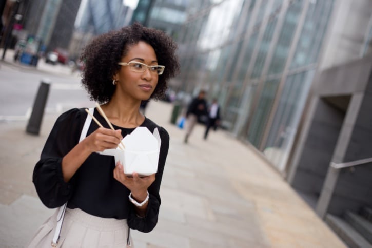 African American woman eating chinese food on the street