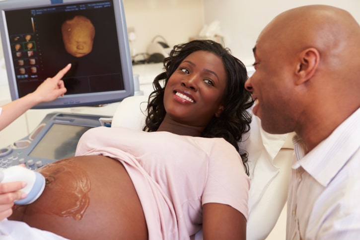African American pregnant woman and man getting ultrasound at doctor office