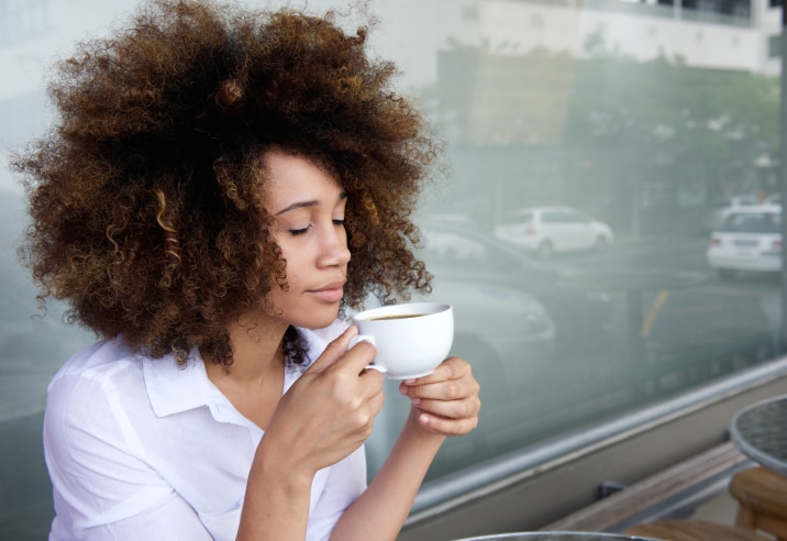 African American woman inhaling cup of coffee tea