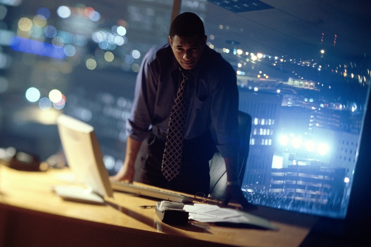 African American businessman standing at desk late night