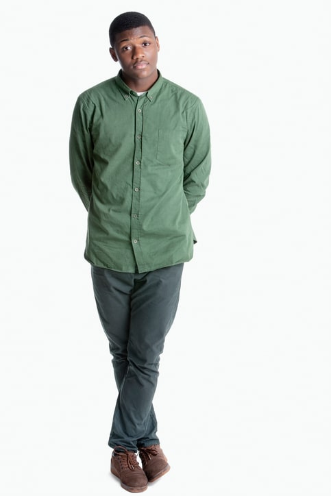 Portrait of a young African American man standing with legs crossed over gray background