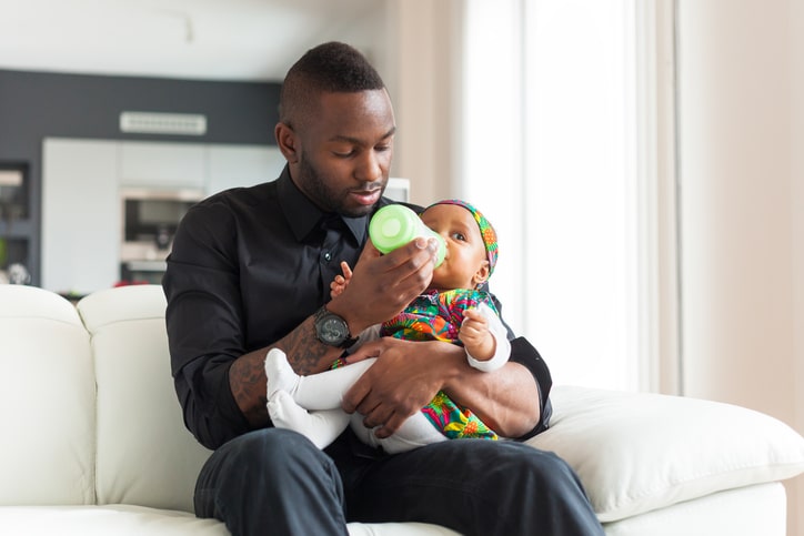 African American father feeding baby girl bottle