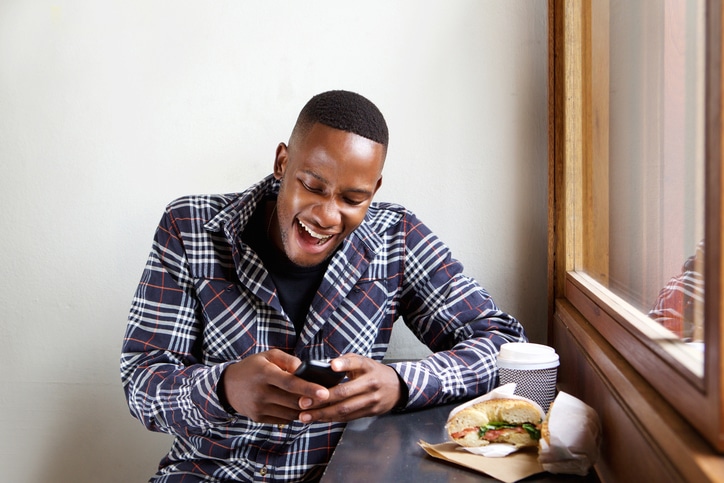 African American man teen reading text eating