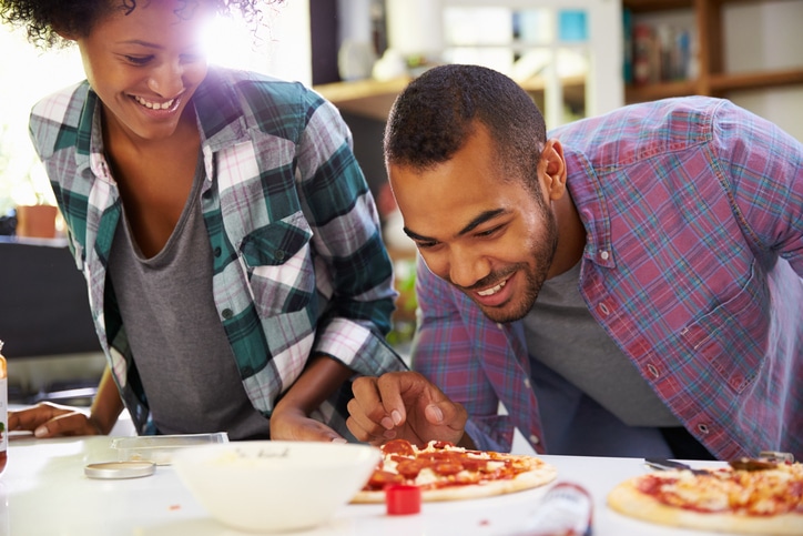 African American couple cooking pizza together