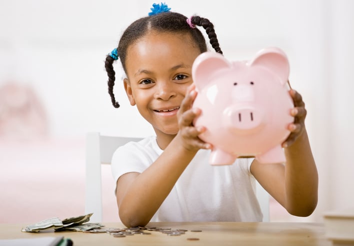 African American girl puts money in piggy bank
