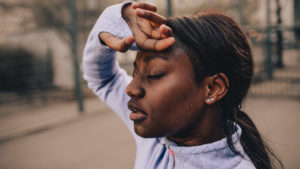 Girl with hand on head exhausted from exercising.