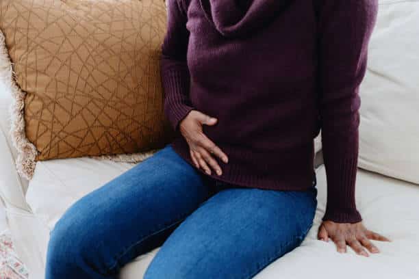 a person sitting on a couch holding her stomach