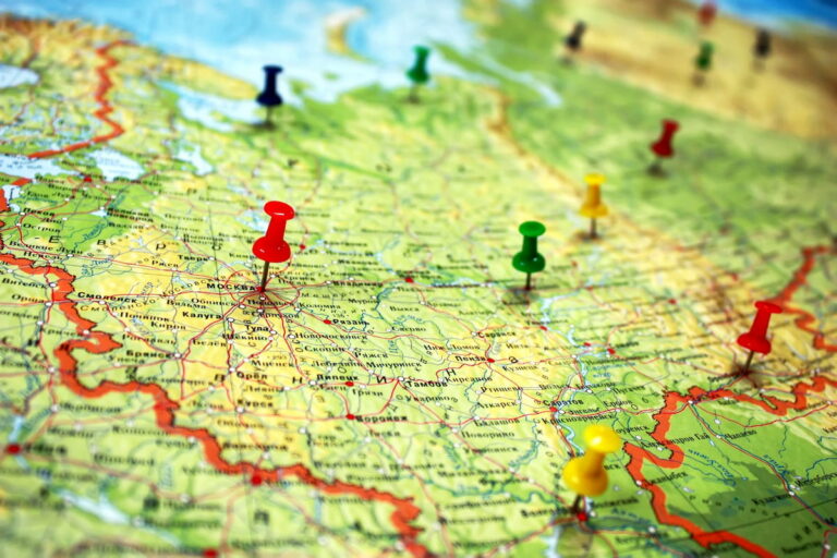 A close-up of a map of Russia with several colorful pushpins, including a red one marking Moscow, indicating travel plans or locations.