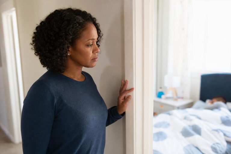 Concerned mother listens at a bedroom doorway during a child’s asthma coughing episode.