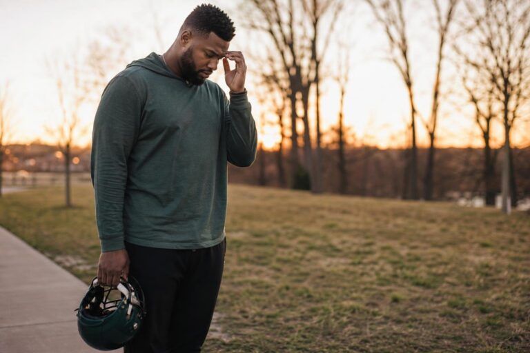 Athletic Black man at a park edge reflects on an AVM brain condition diagnosis.